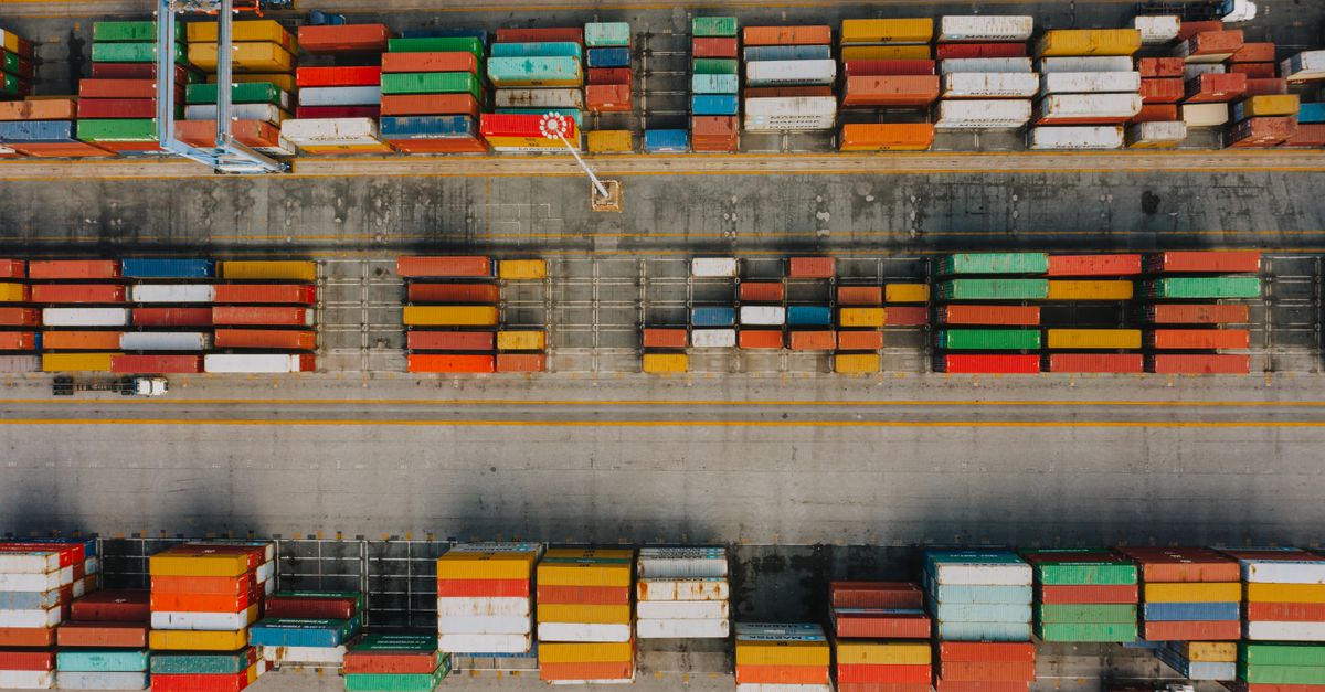 Drone view of various colorful cargo containers placed in rows on asphalt in daytime