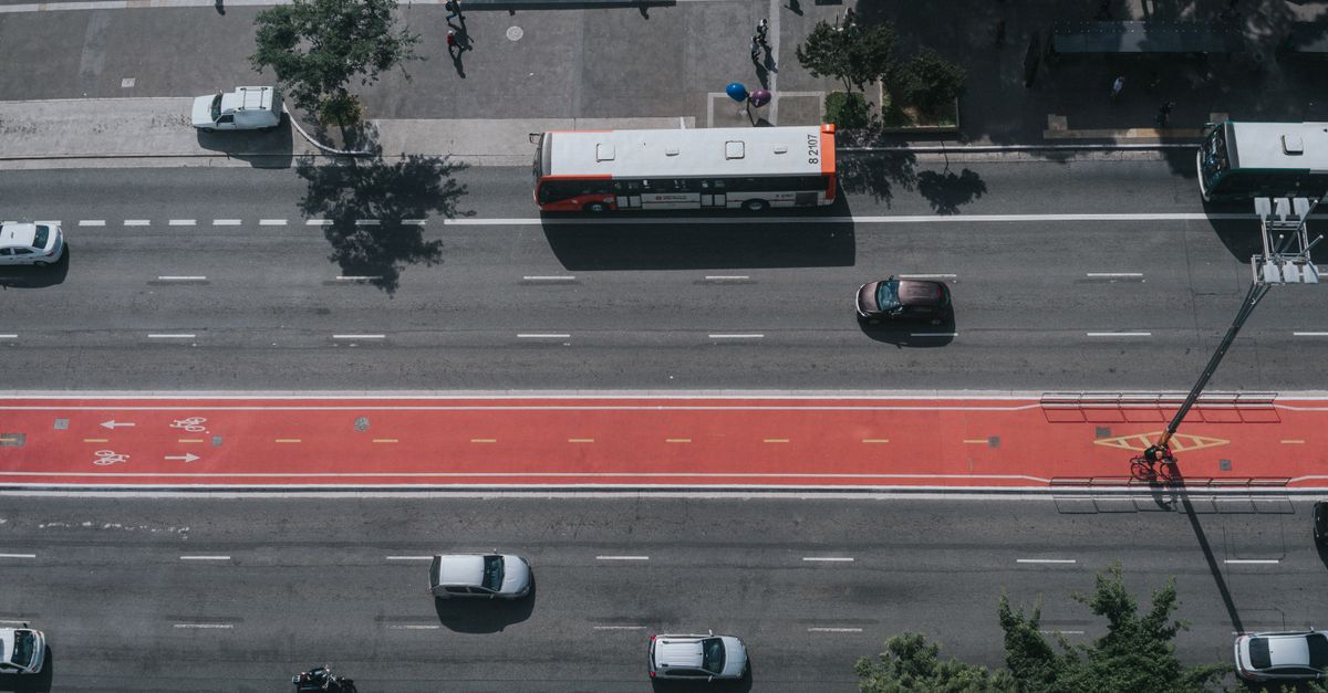 Aerial perspective of city traffic showcasing cars, buses, and bike lanes on a major roadway.